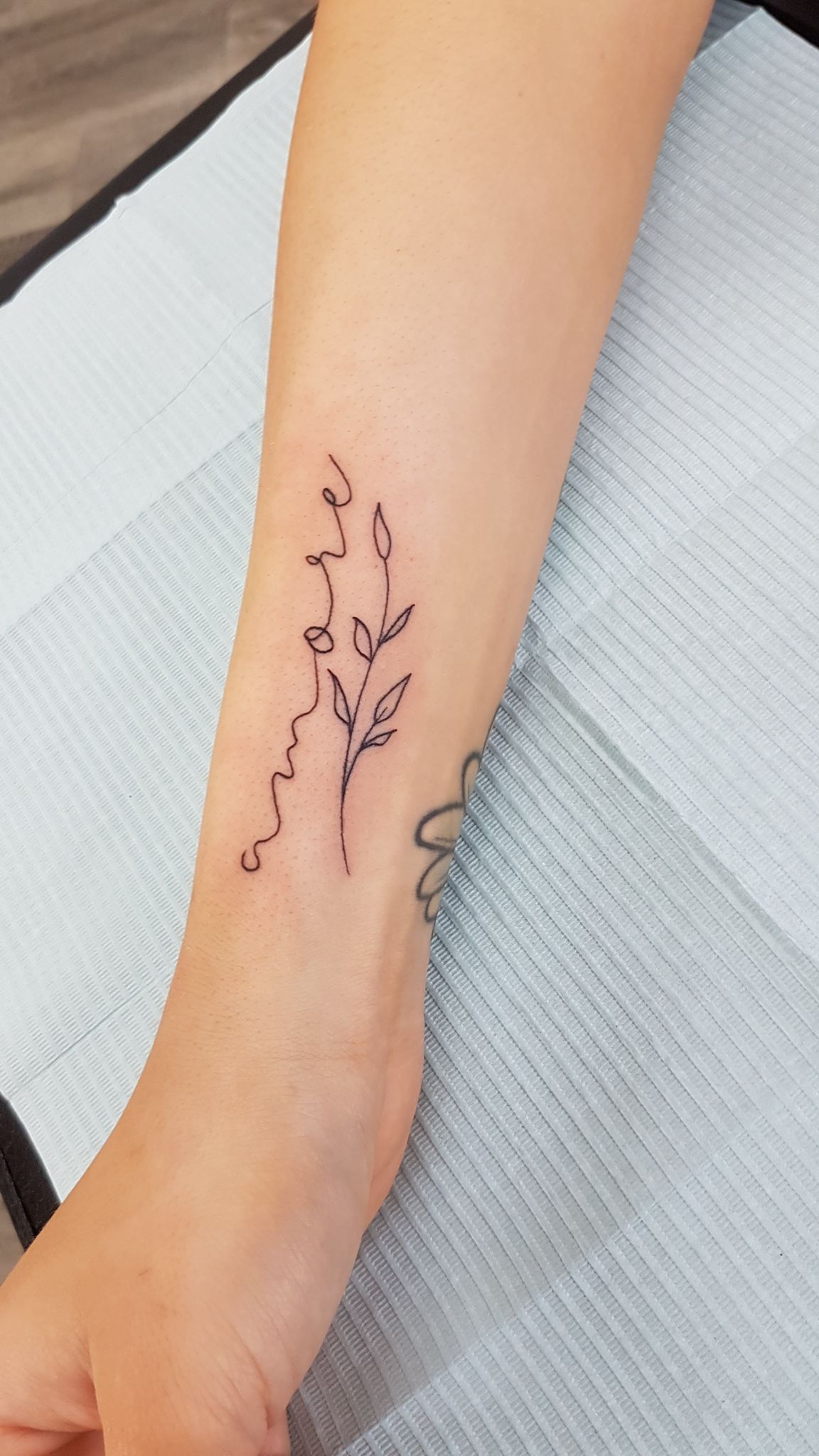 Black and white upper arm script tattoo