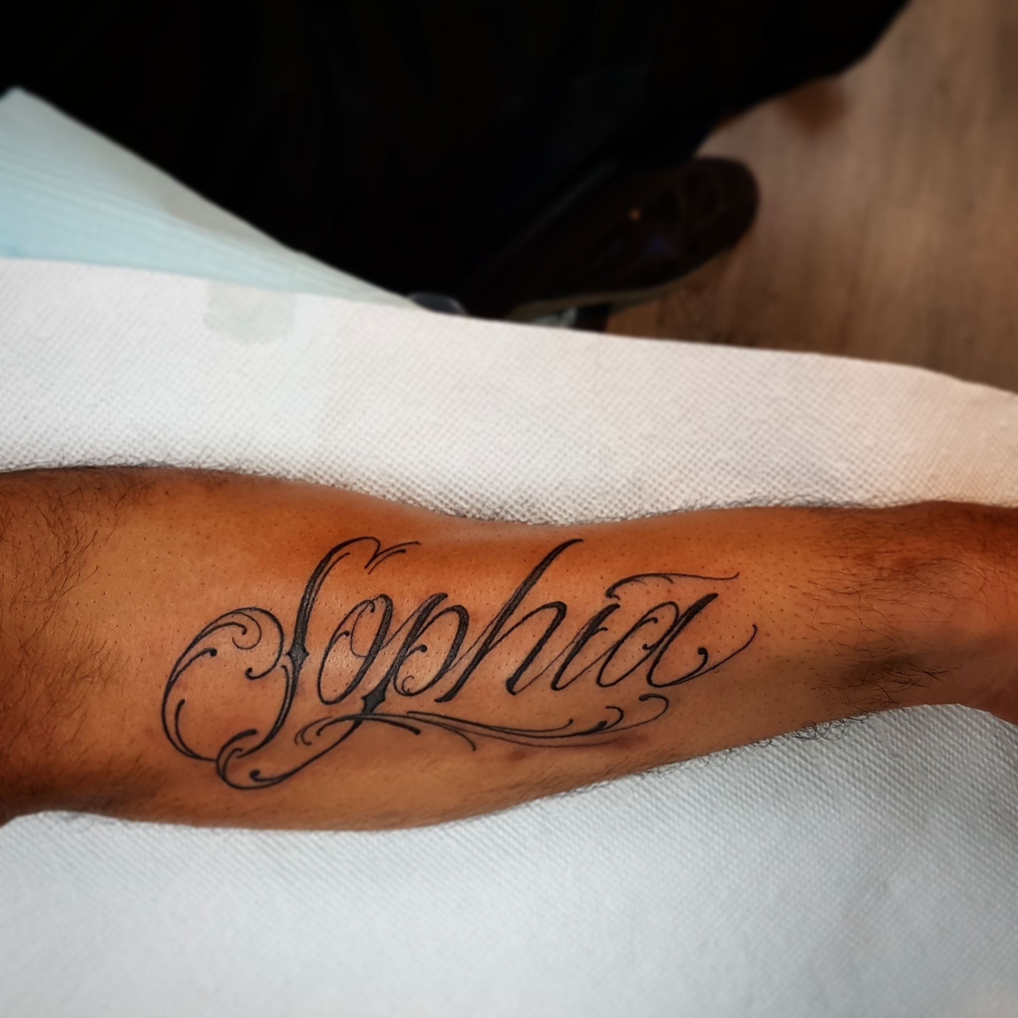 Black and white upper arm script tattoo