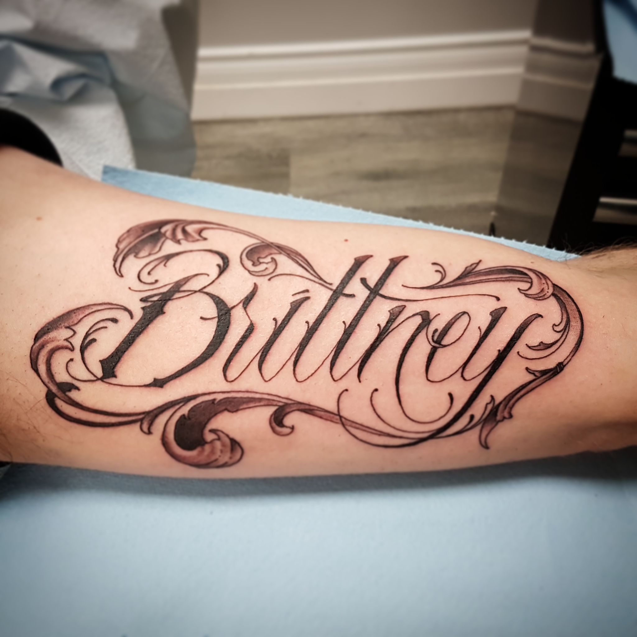 Black and white upper arm script tattoo