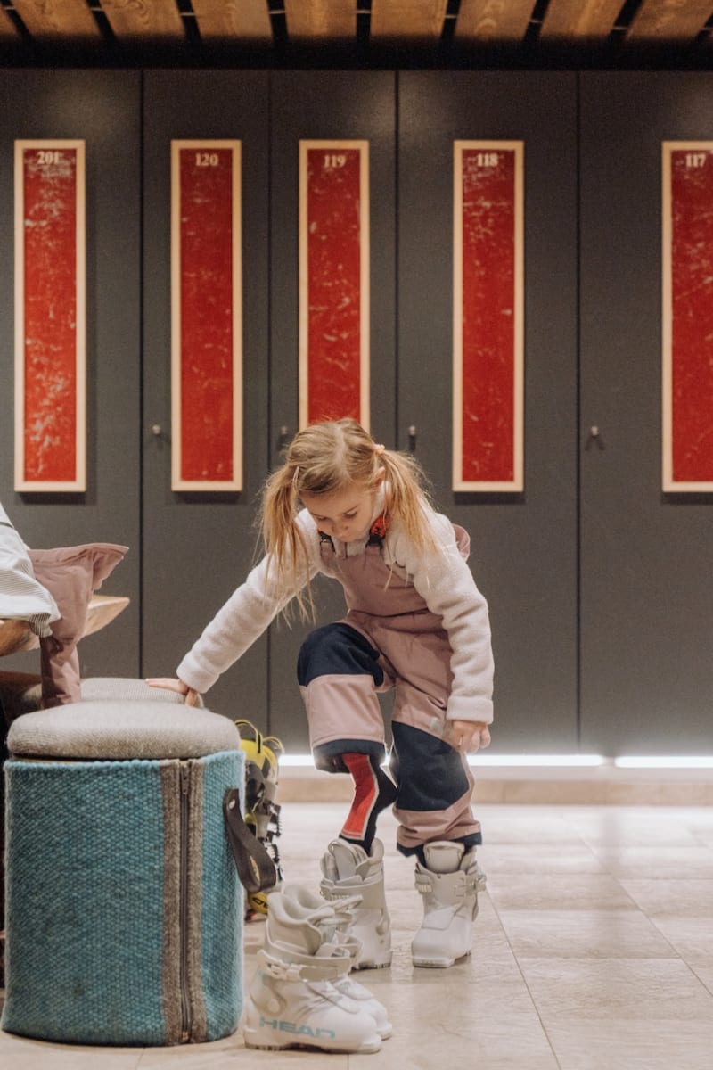 Ein Mädchen zieht Skischuhe an, bereit für den Skispaß im Glemmtal, möglicherweise im Glemmtalerhof.