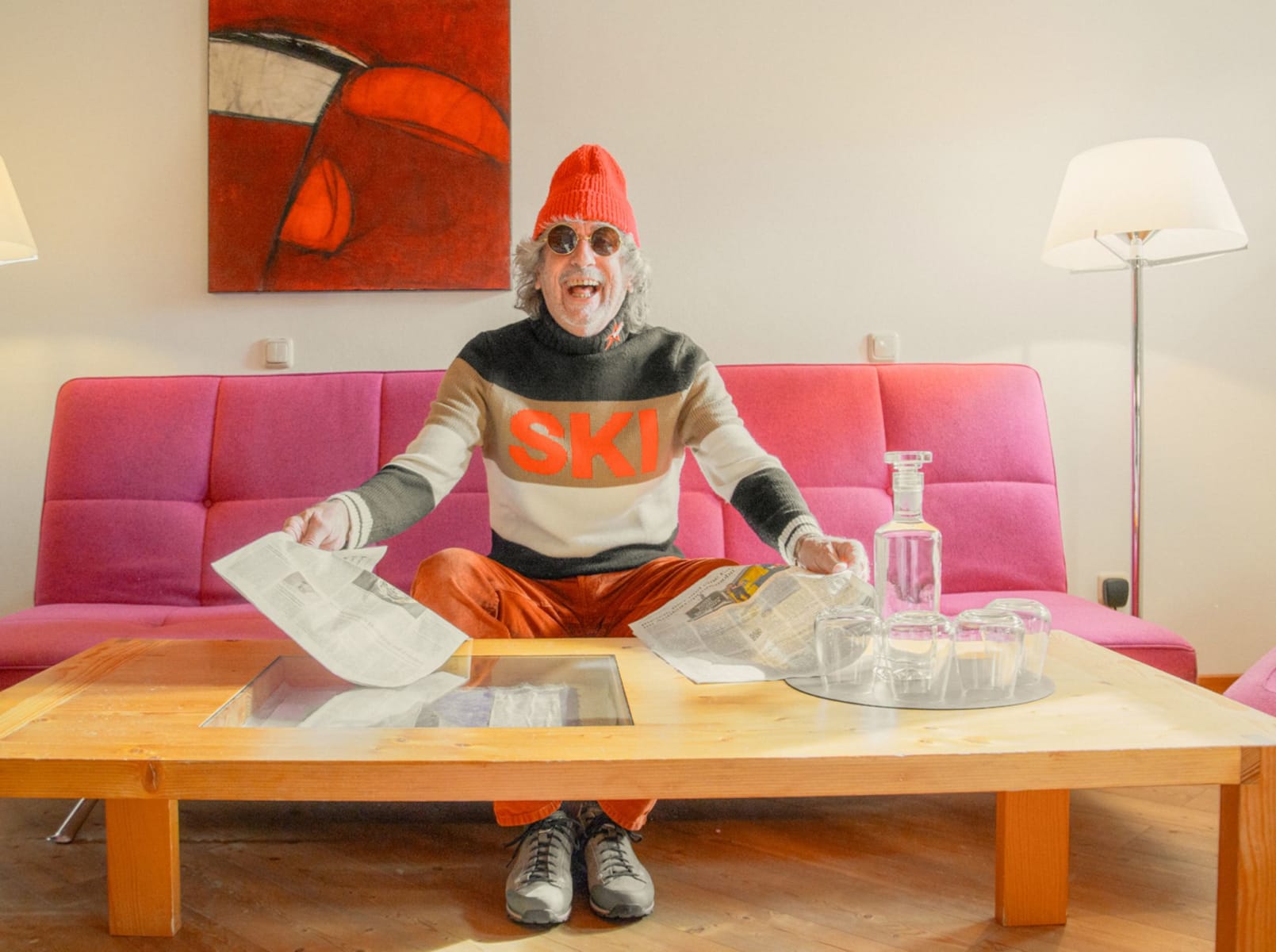 A cheerful man in a ski sweater sits in Glemmtalerhof reading newspapers.