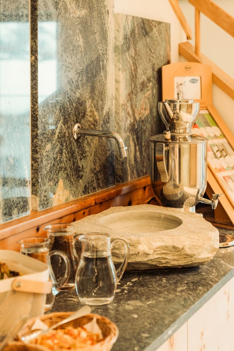 A stylish area in the Glemmtalerhof with a stone bowl and glass jugs.
