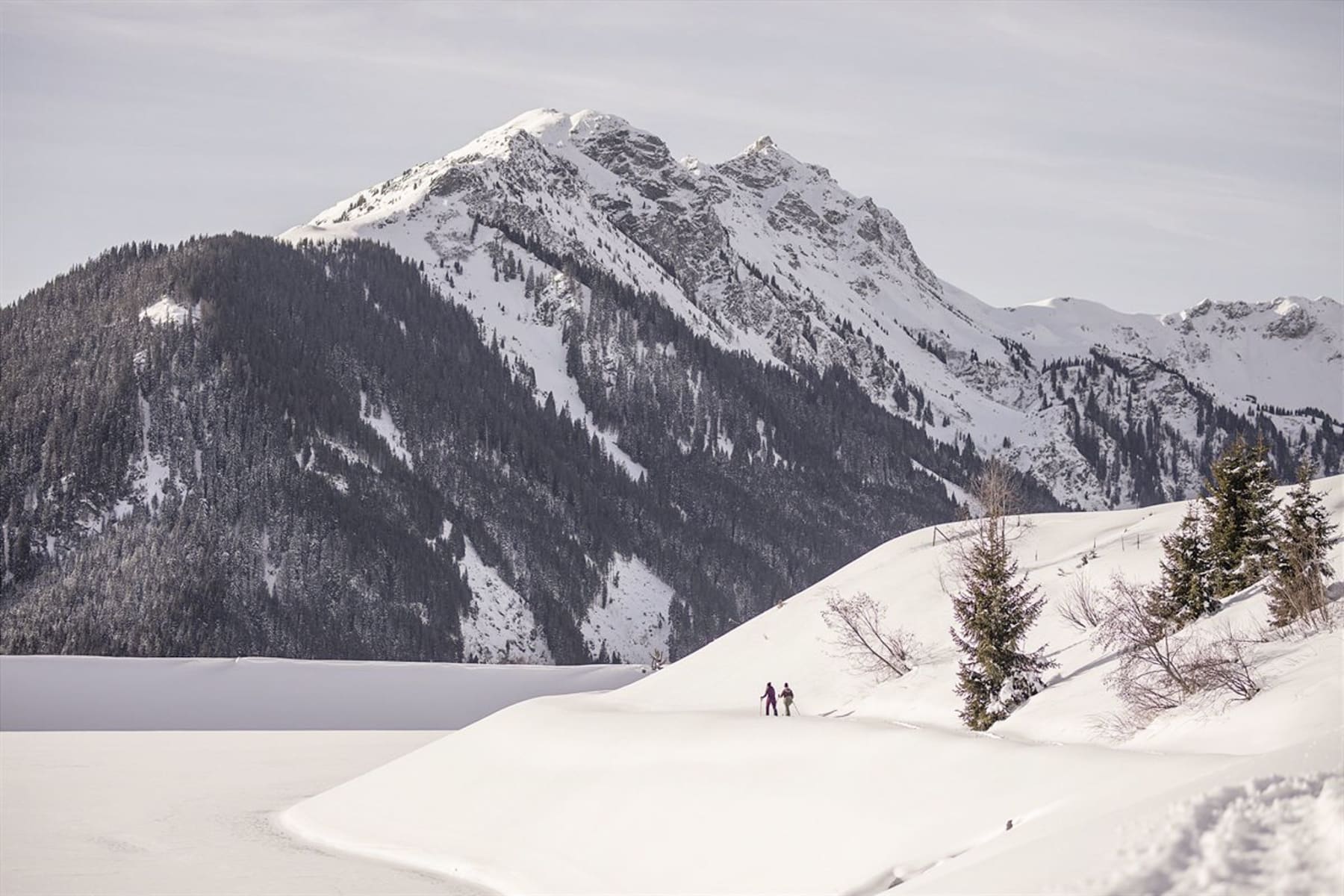 Winterlandschaft im Glemmtal mit Wanderern und schneebedeckten Bergen.