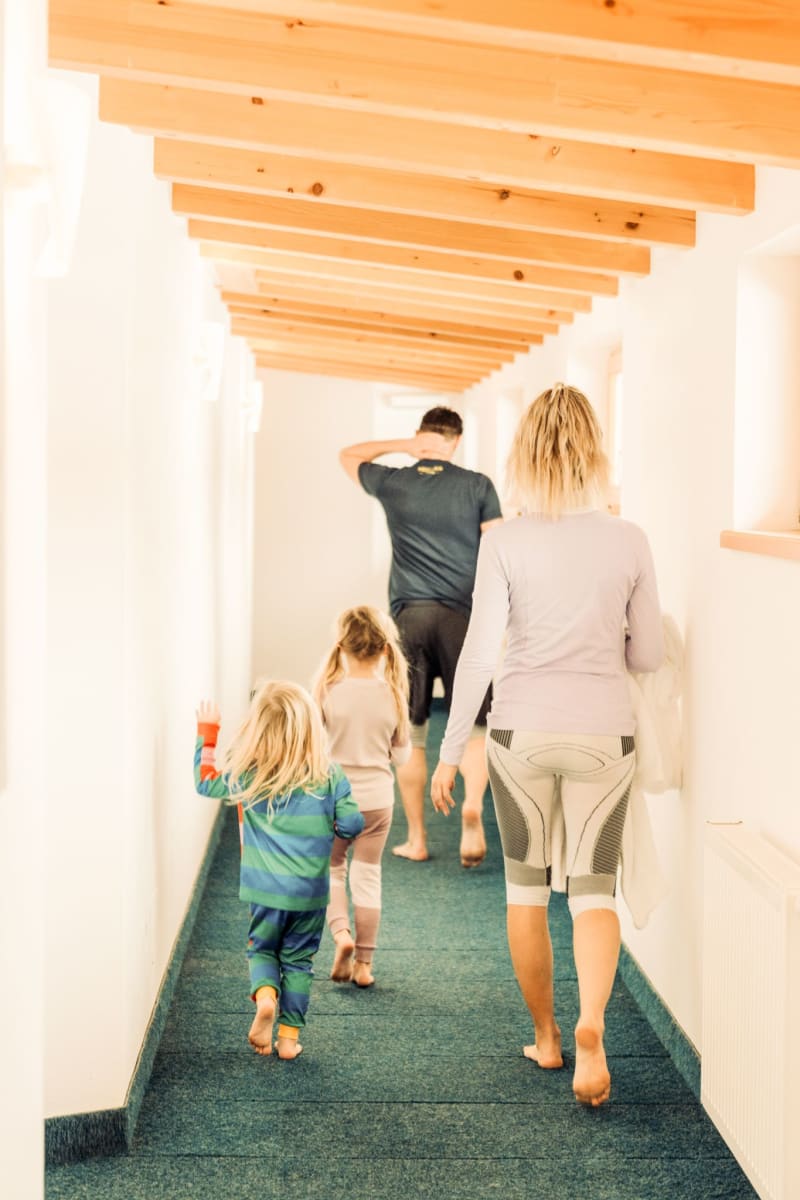 Eine Familie geht im Glemmtalerhof in Hinterglemm einen hellen Flur entlang.