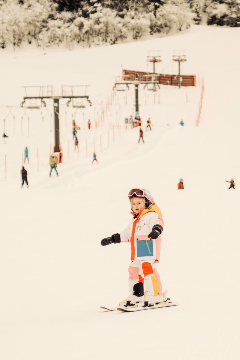 Ein Mädchen fährt Ski im Glemmtal, mit einem Skilift im Hintergrund.