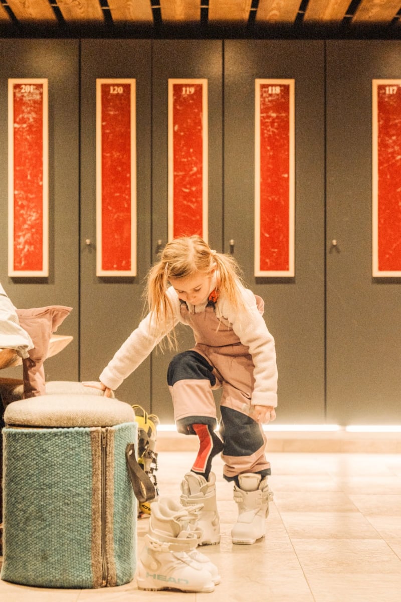 Ein Mädchen zieht sich Skischuhe im Glemmtalerhof in Hinterglemm an.