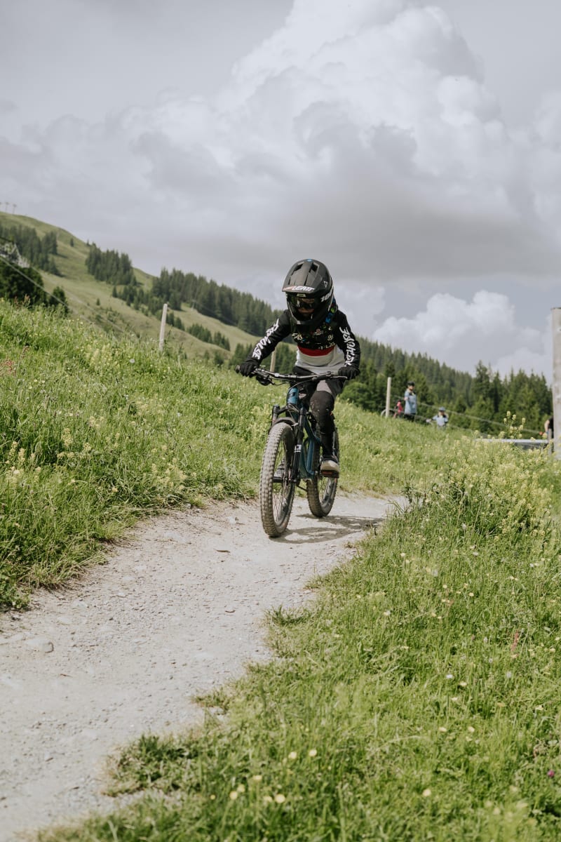Ein Jugendlicher fährt mit seinem Mountainbike auf einem Weg im Glemmtal.