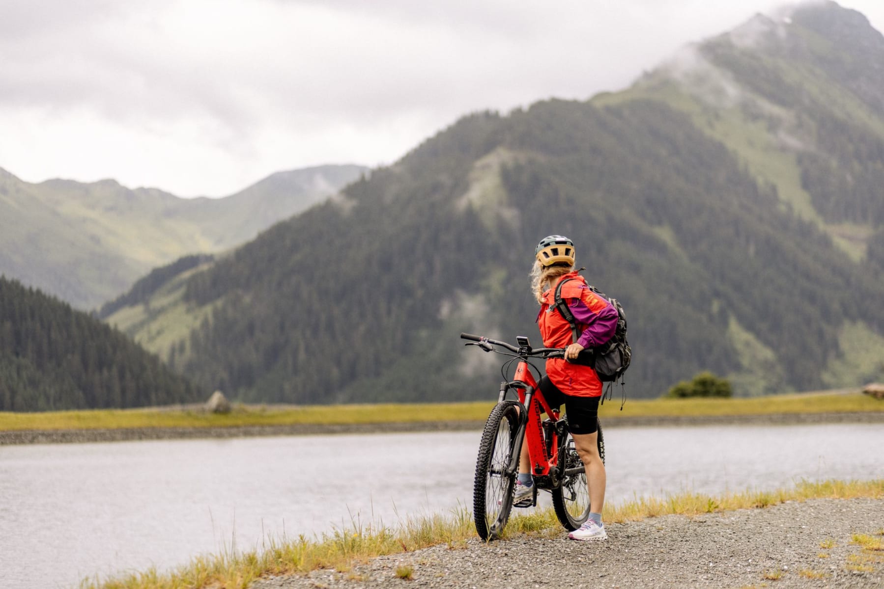 Ein Radfahrer am Glemmtalerhof in Hinterglemm schaut auf die Berge und den See.