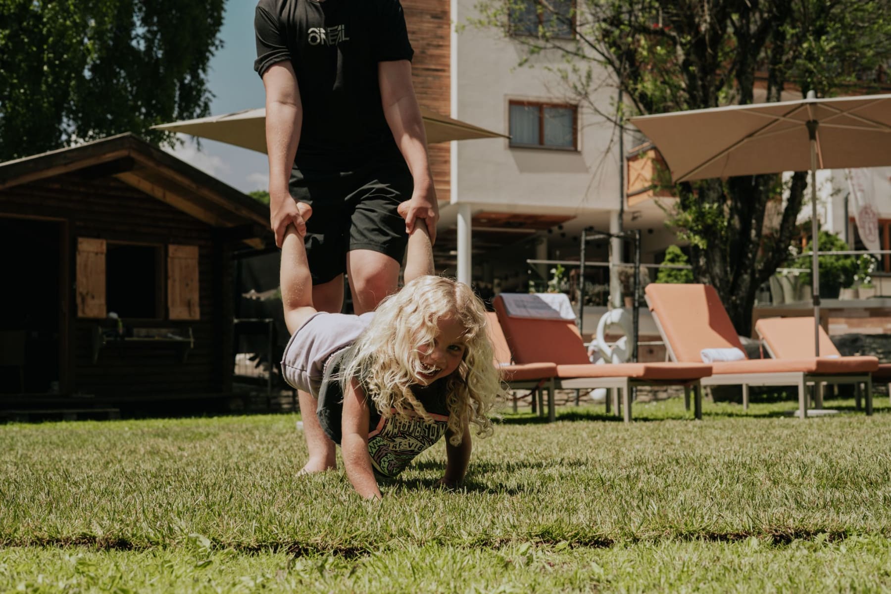 Ein Kind spielt im Glemmtal, während ein Erwachsener es fröhlich anhebt.