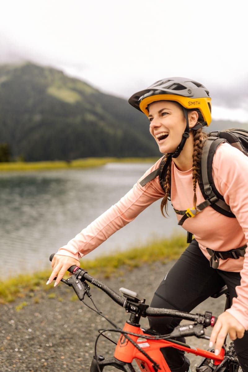 Eine Frau fährt mit dem Fahrrad am Glemmtalerhof in Hinterglemm. Freude und Natur sind spürbar.
