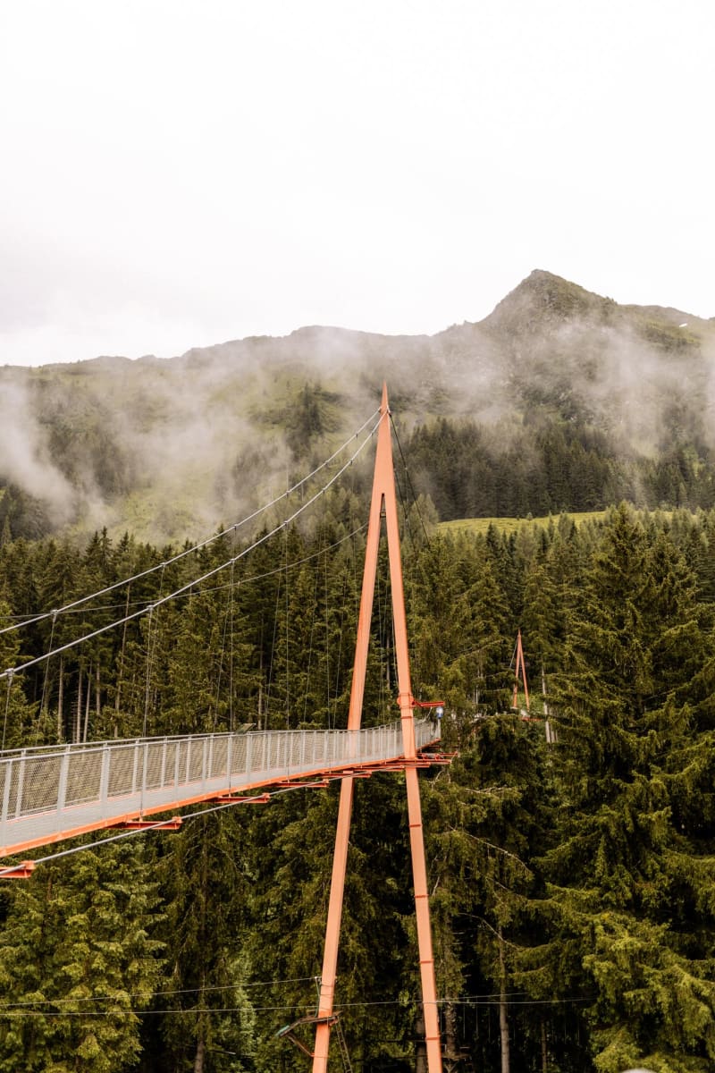 Suspended hanging bridge in Glemmtal, surrounded by dense forests and mountains.