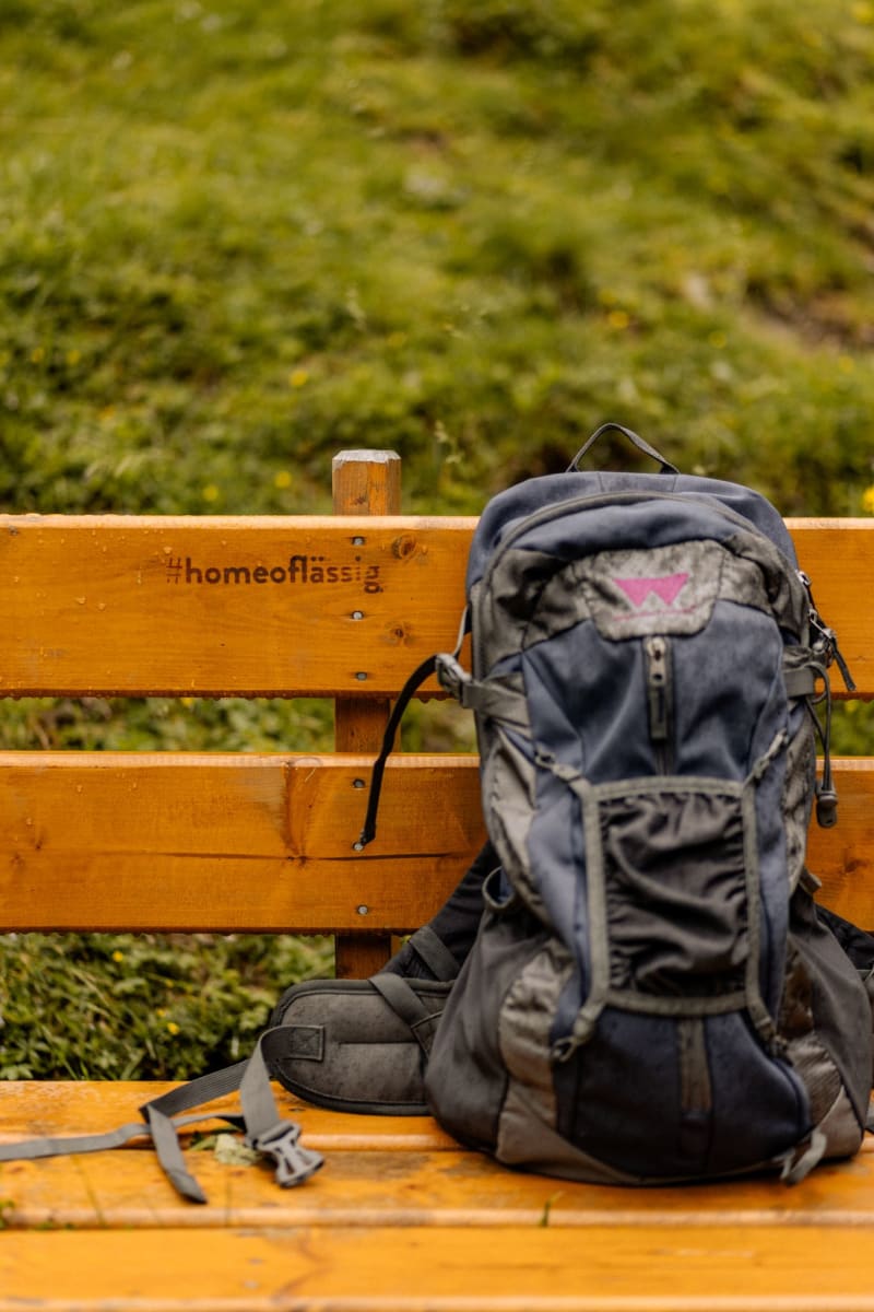 Rucksack auf einer Bank im Glemmtal, Natur umgeben. Einladender Ort für Wanderer.