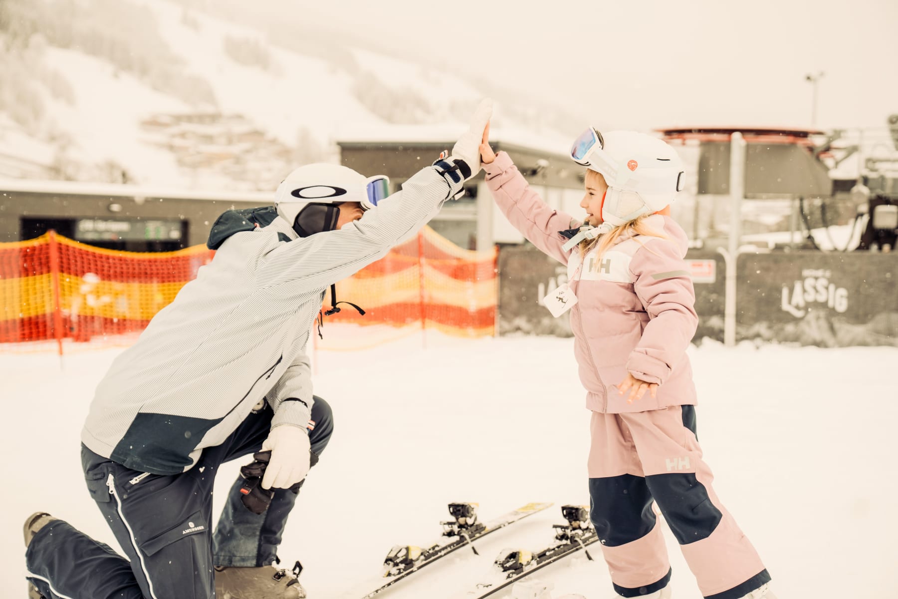 Ein Erwachsener und ein Kind feiern auf der Piste im Glemmtal.