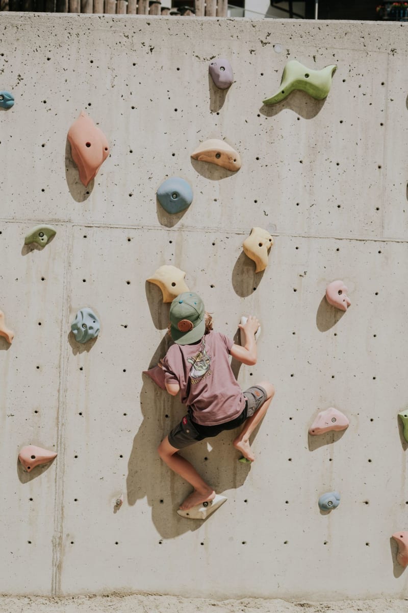Ein Kind klettert an einer Kletterwand im Glemmtal.