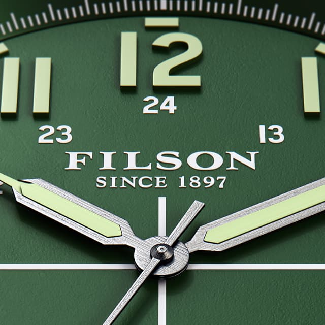 Close up Filson watch with light green numbers in a dark green background