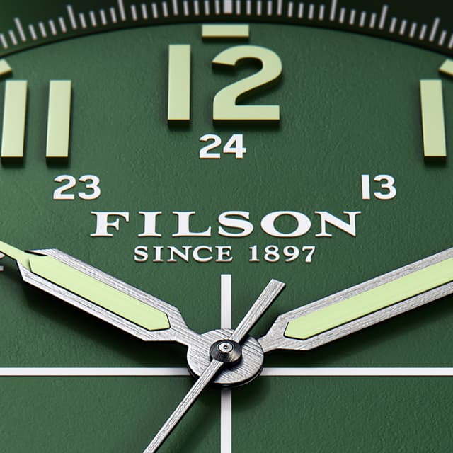 Close up Filson watch with light green numbers in a dark green background