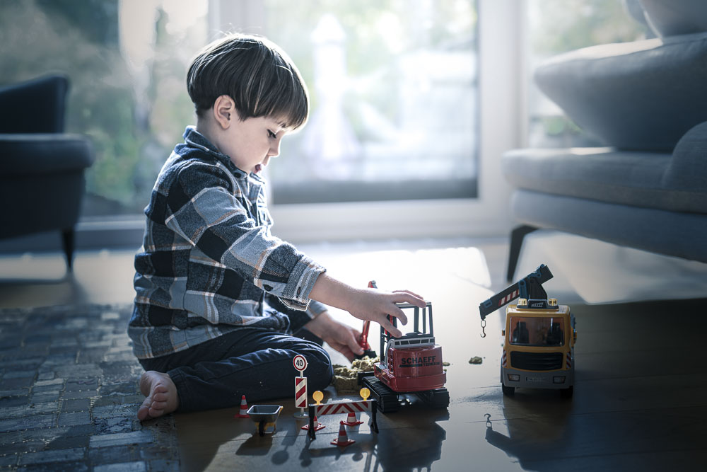 Junge spielt mit Baufahrzeugen im Wohnzimmer