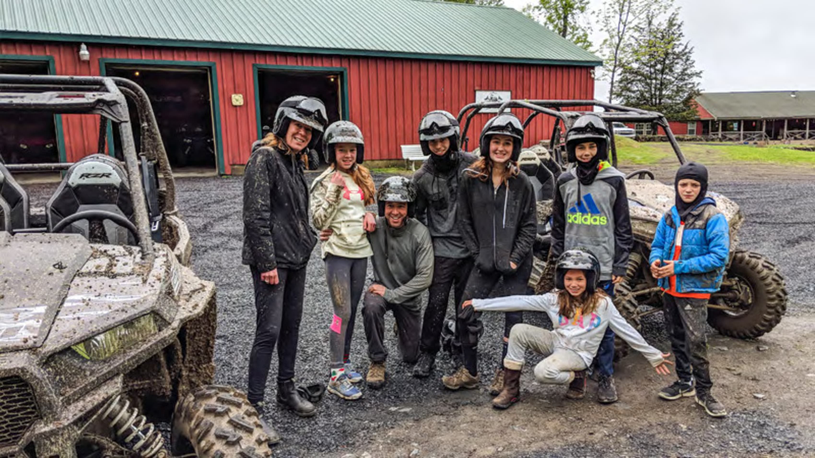 Group of people wearing helmets ready for an off-road adventure, standing in front of an all-terrain vehicle.