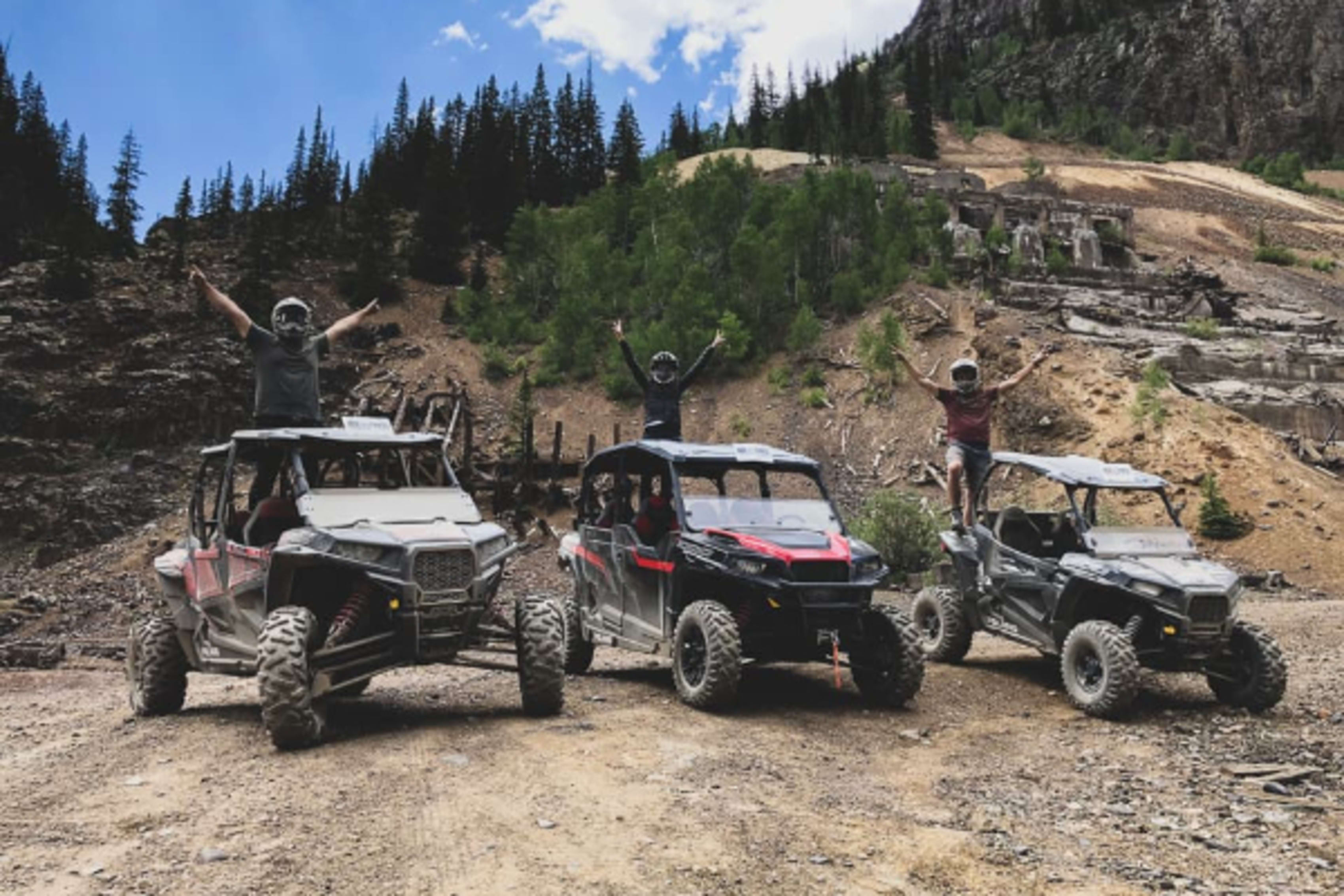 Polaris RZRs parked with riders standing on top