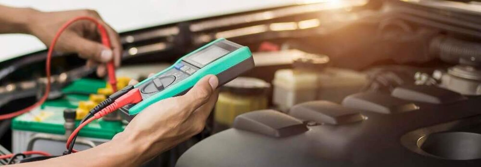 Person sjekker bilbatteriet med et multimeter.