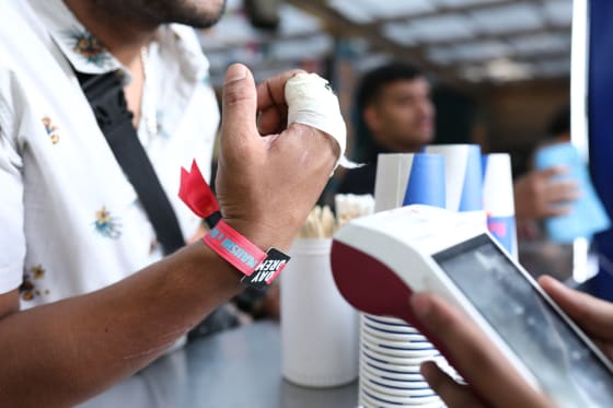 Attendee wearing an RFID wristband tapping to pay at a bar counter POS terminal using AtomX NFC contactless payments