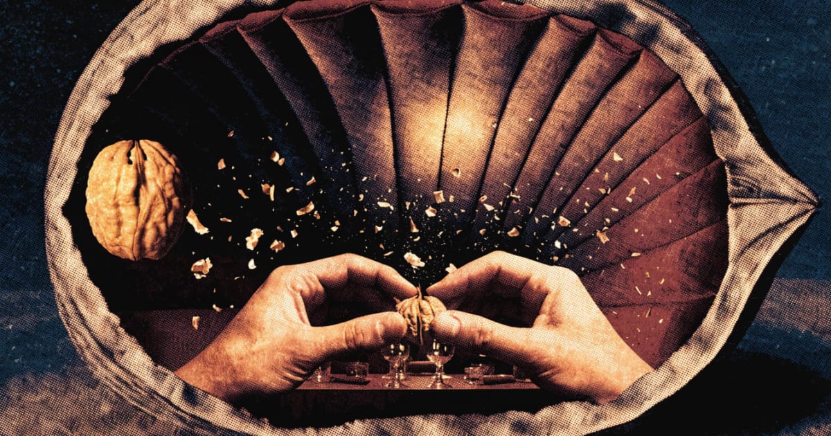 A pair of hands crack a walnut open at a tiny candlelit dining table built inside an enlarged walnut shell's interior.