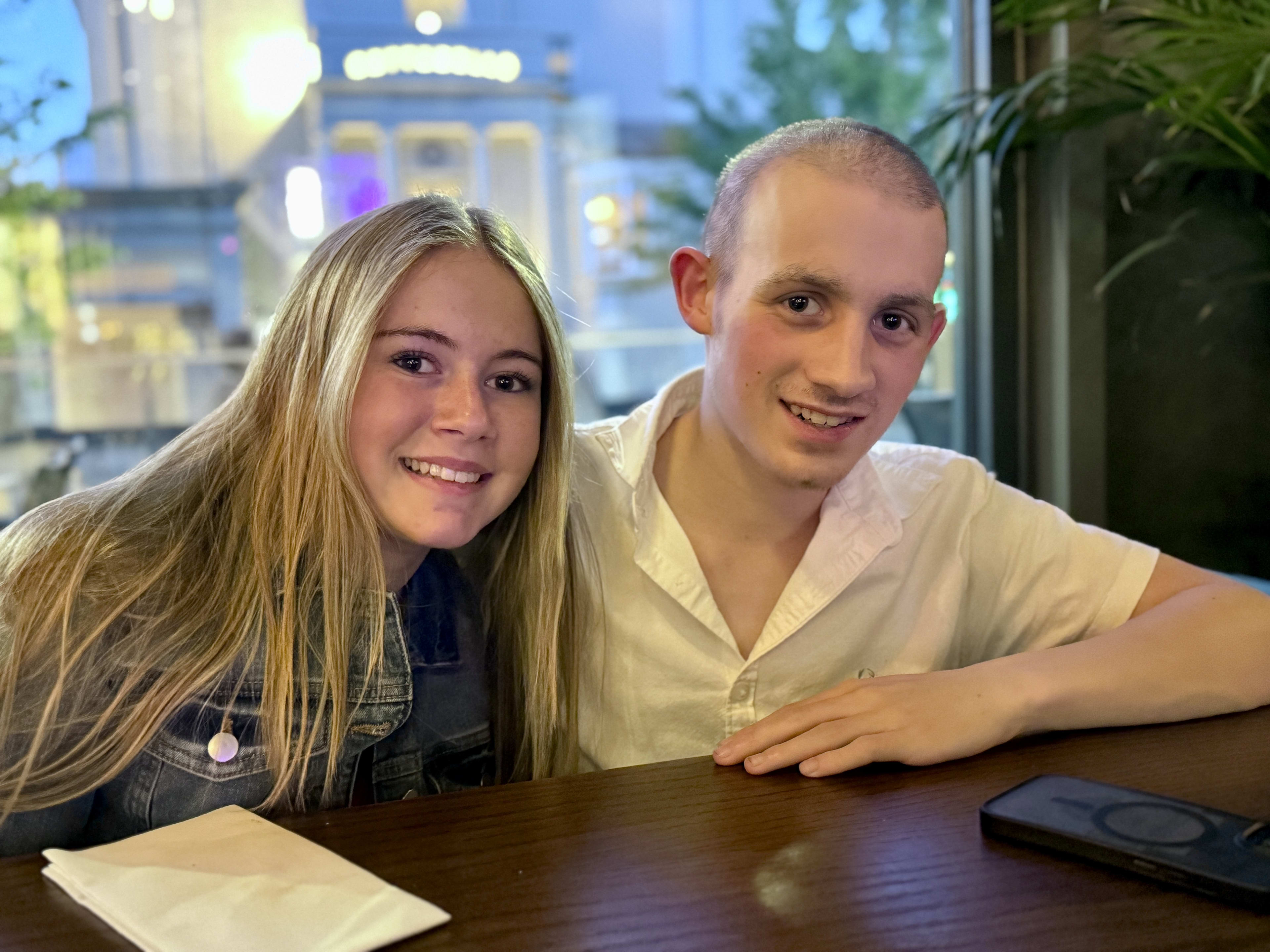 Charlie and Amelia at a restaurant, city lights behind them