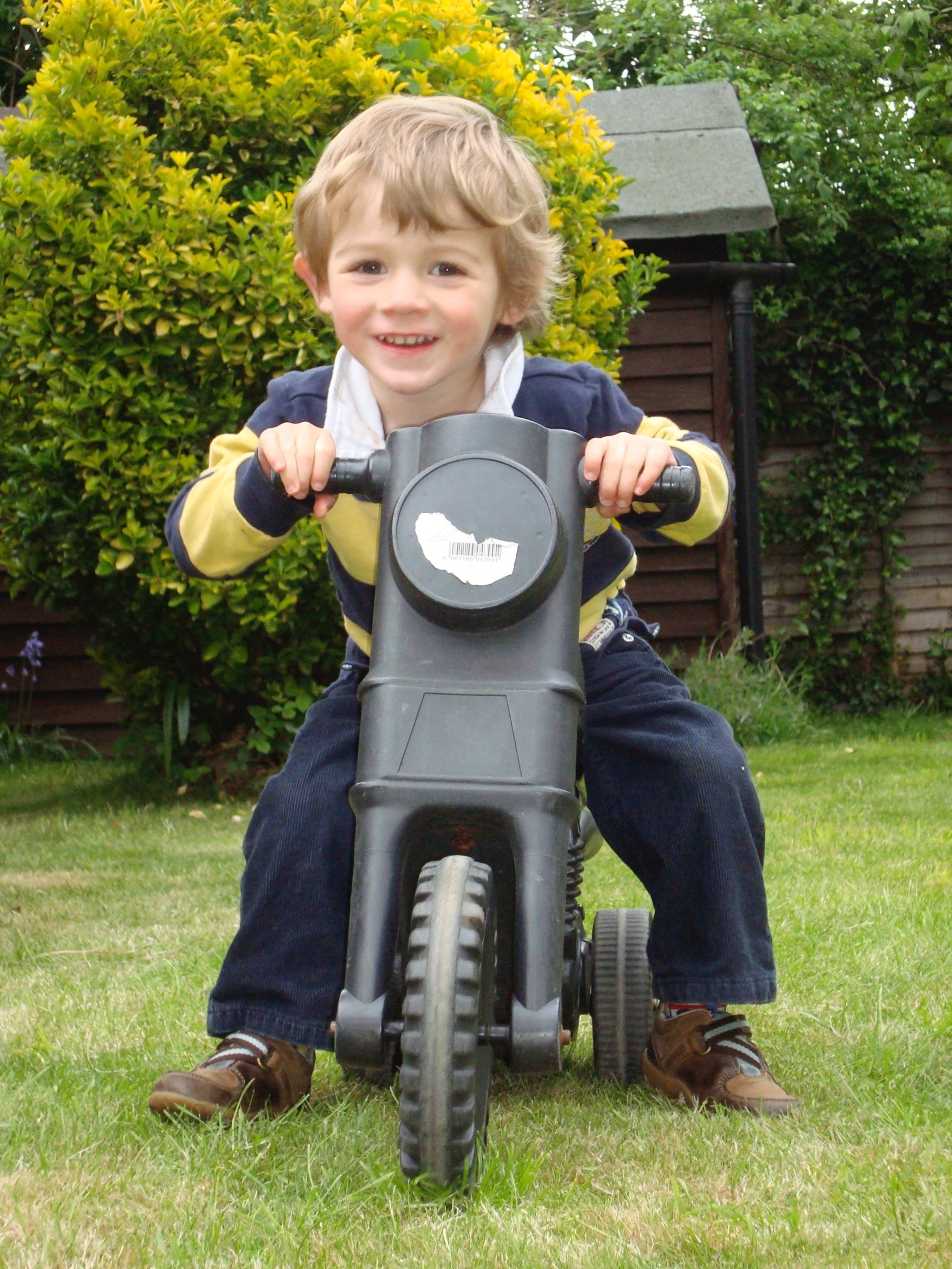 Young Charlie on a toy motorcycle in the garden