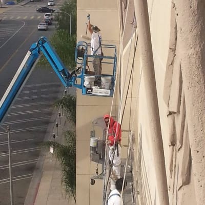 Painter working at height from a boom lift in full personal protective equipment