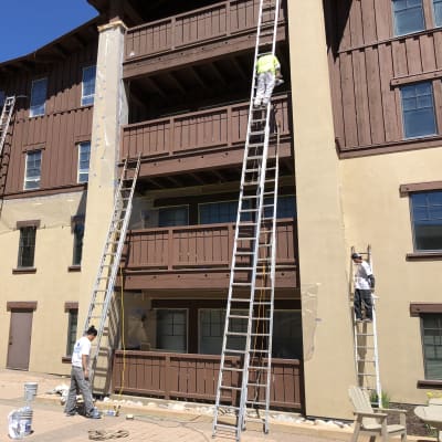 Moorhouse Coating crew staining a multi-story exterior from ladders