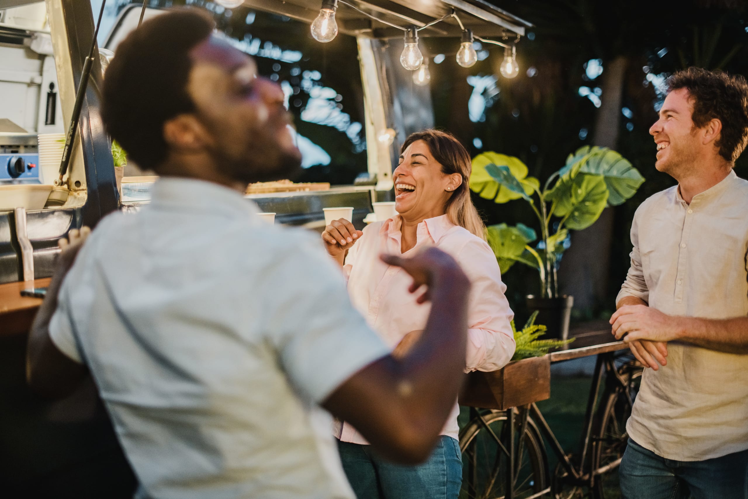 diverse-friends-laughing-outside-food-truck-in-eve-2022-09-29-22-22-44-utc