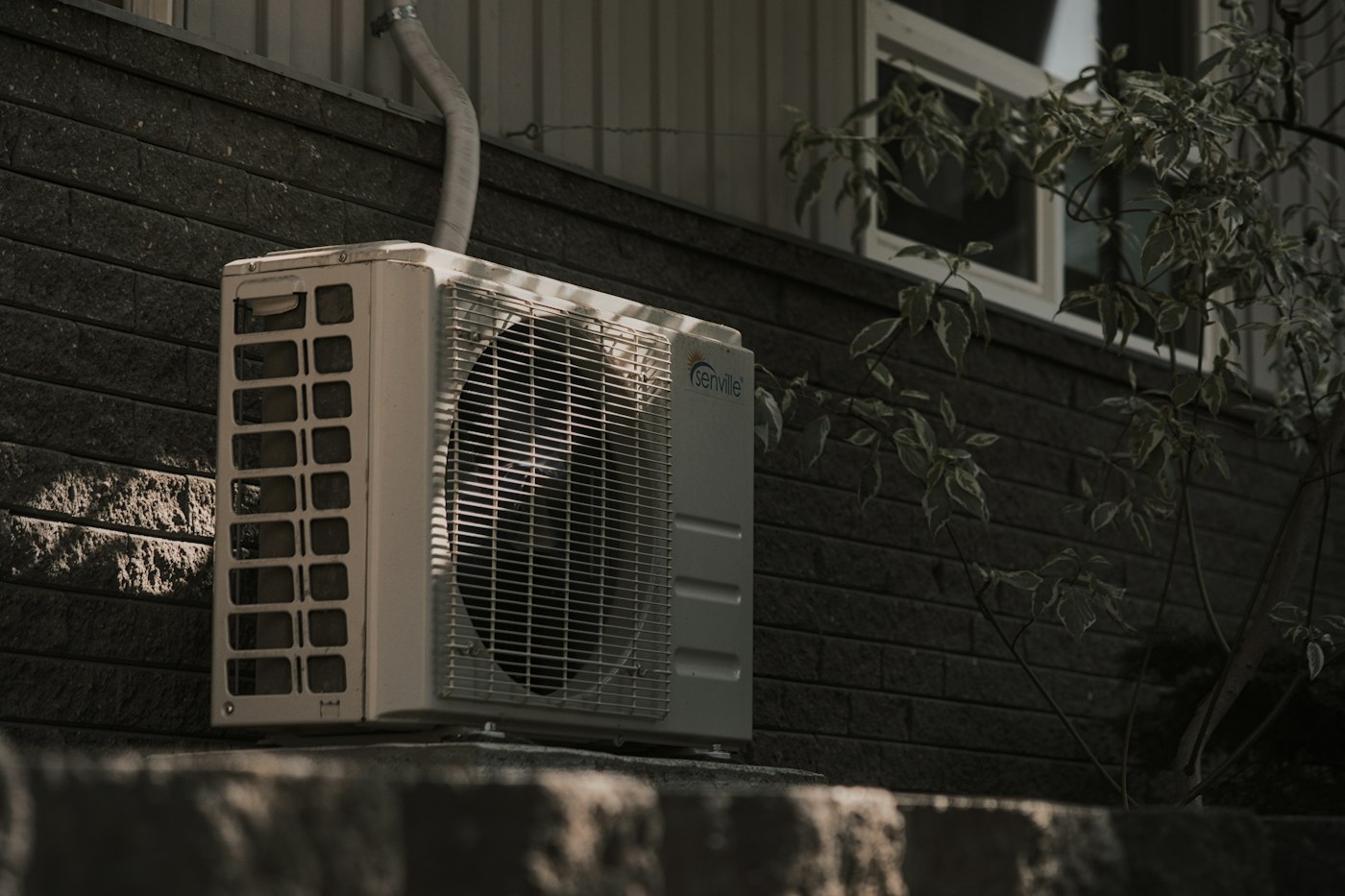 a white air conditioner sitting on top of a brick wall