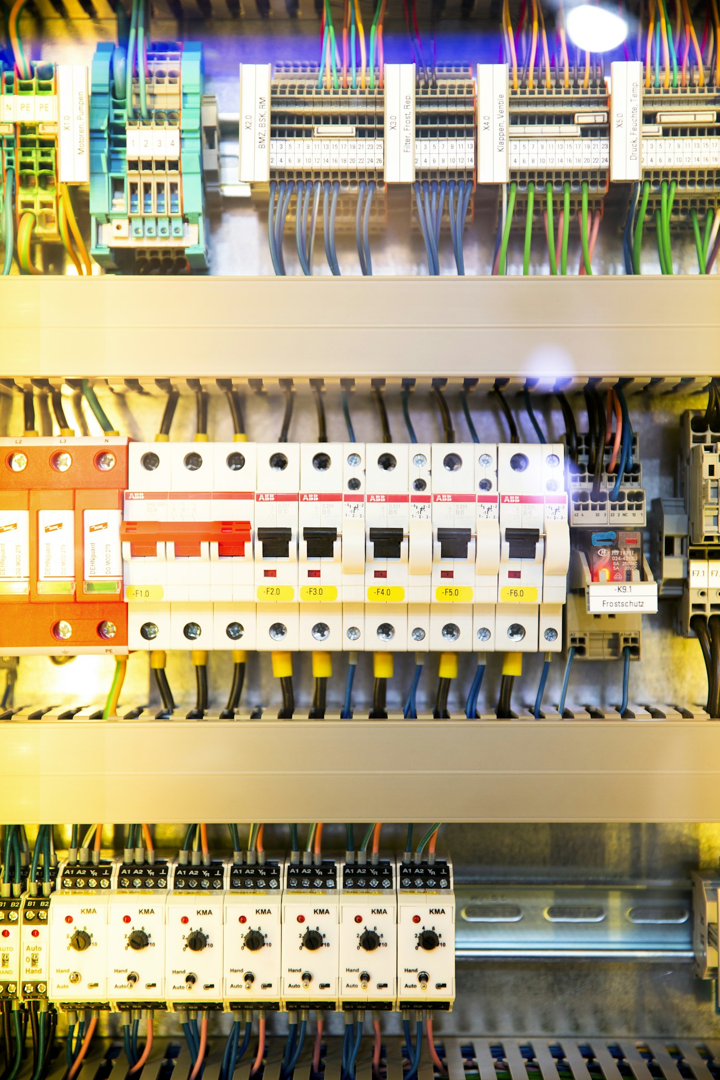 An electrical switch box with circuit breakers and colorful wiring in a control panel