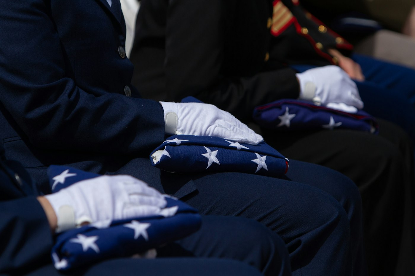People in uniform carefully fold american flags
