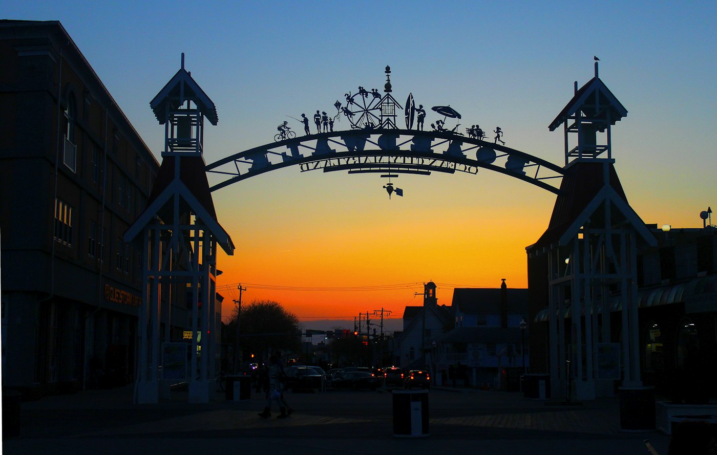 A sunset view of a building with a large metal arch