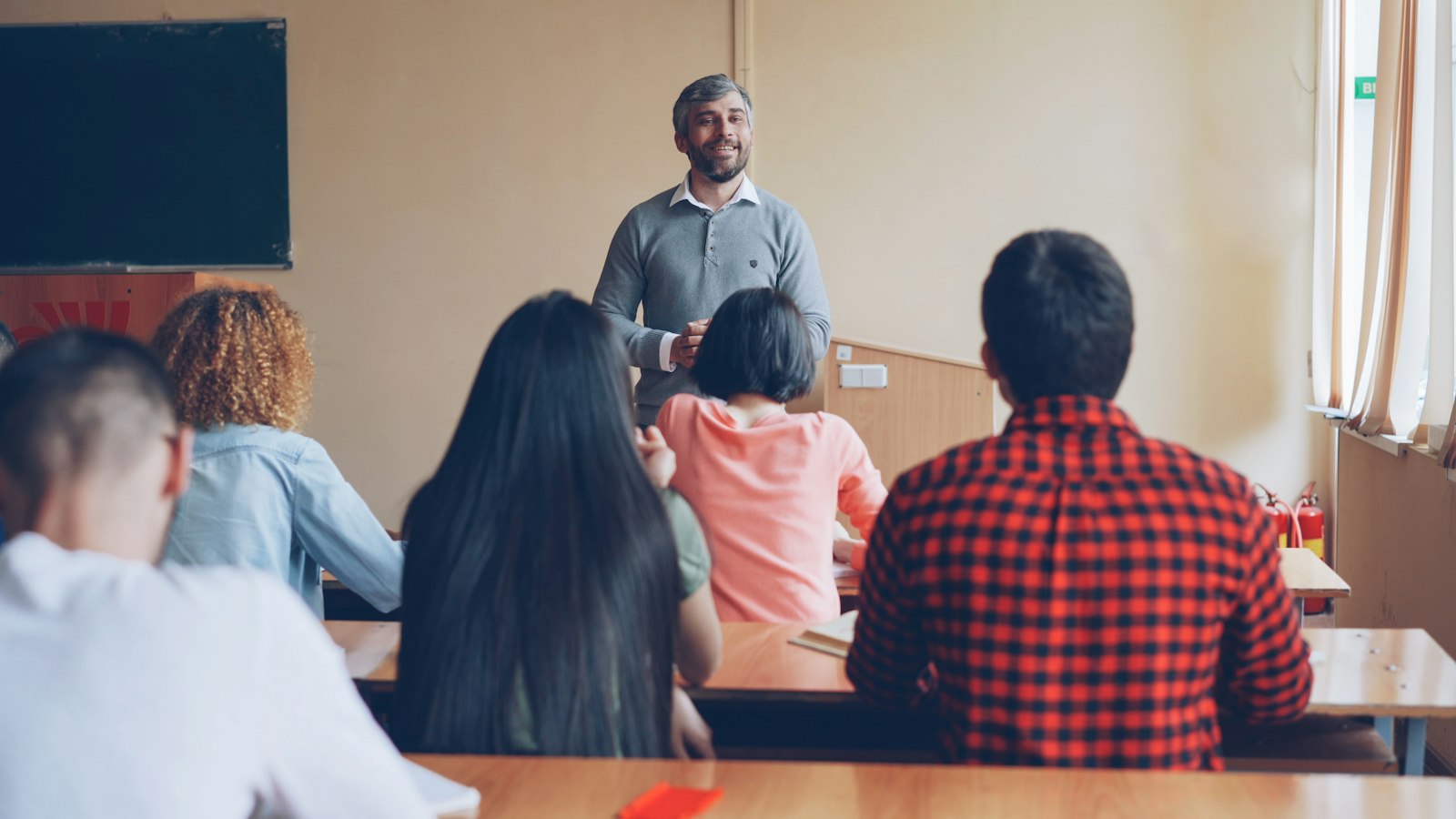 A teacher standing at the front of a classroom while students sit at desks