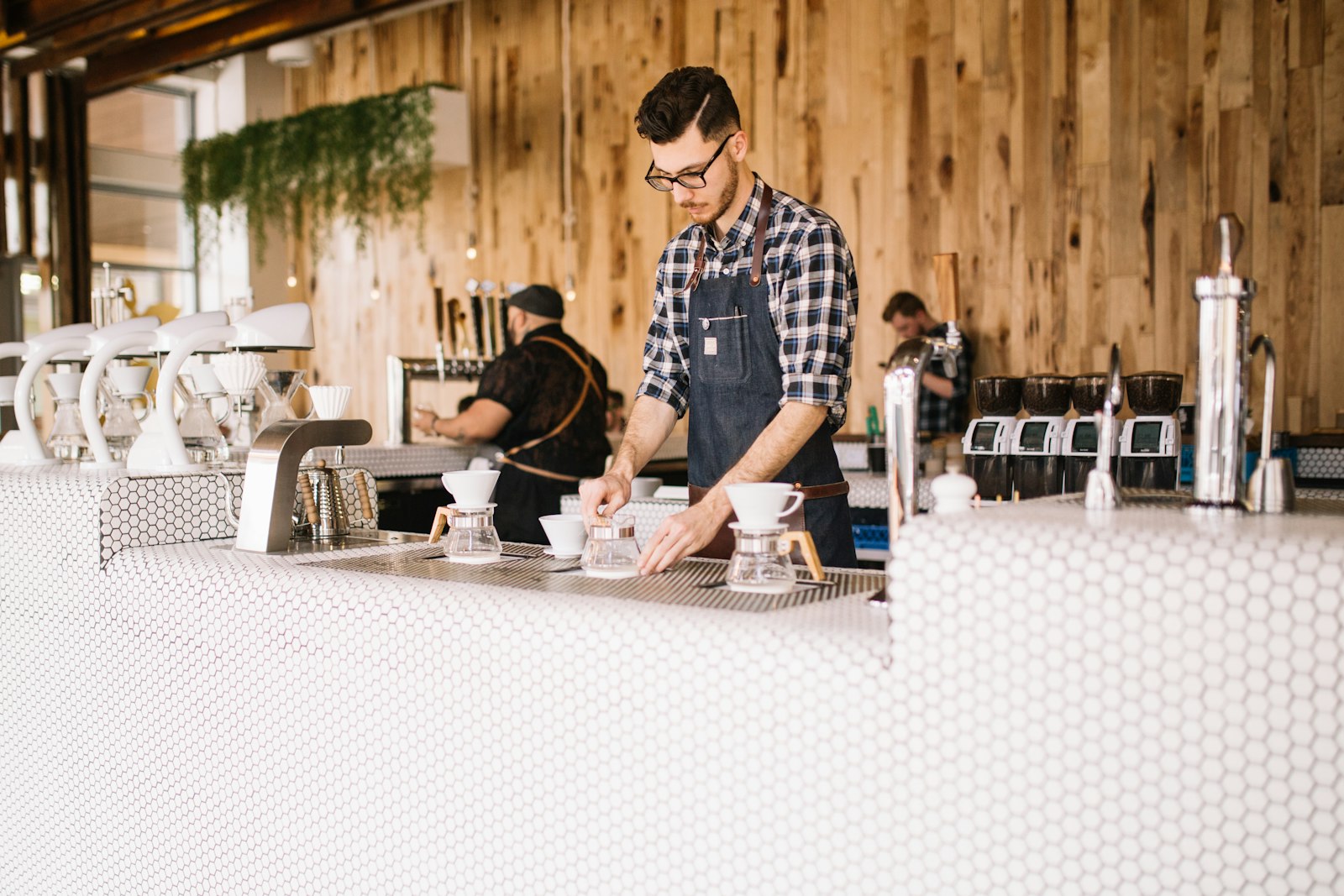 A barista in an apron preparing pour-over coffee behind a cafe counter