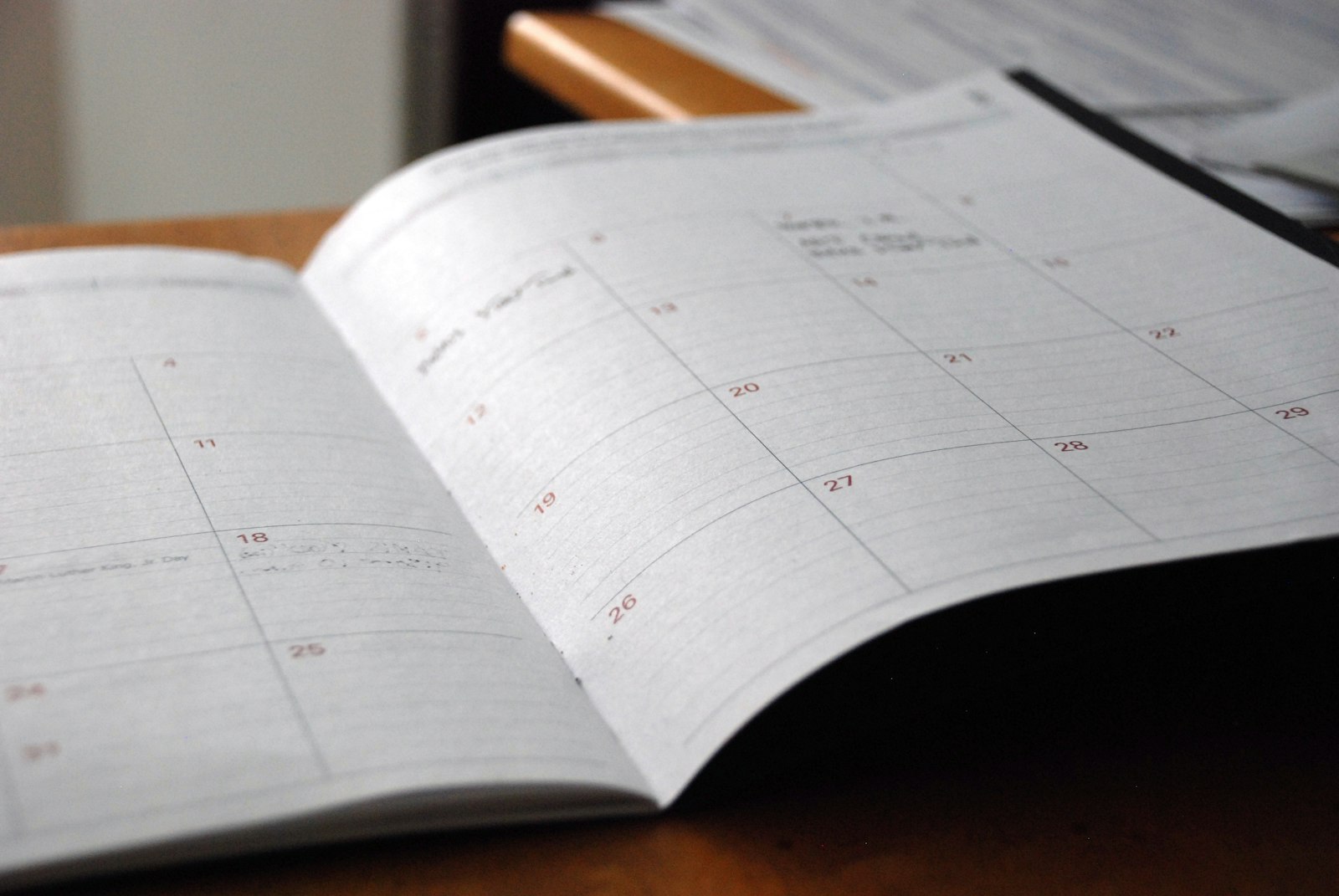 An open monthly paper planner on a wooden desk