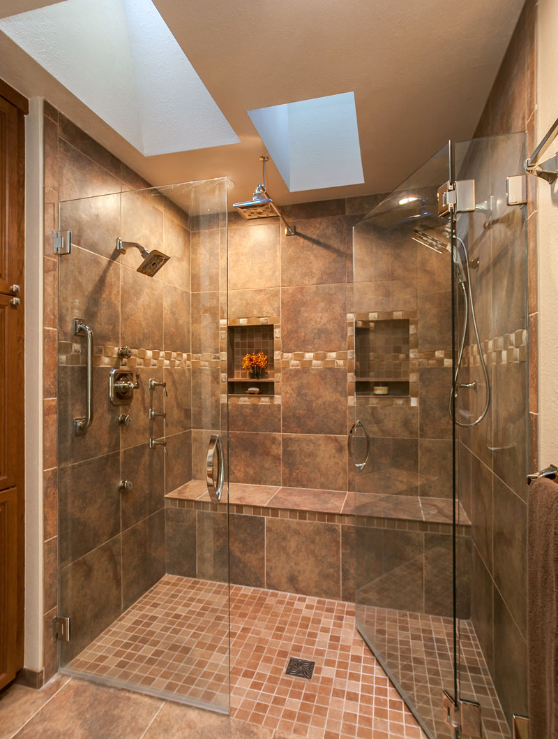 Shower trends 2024 featuring a dual shower system with rainfall showerheads, body jets, and glass enclosures, creating a luxurious and spa-like bathroom experience.