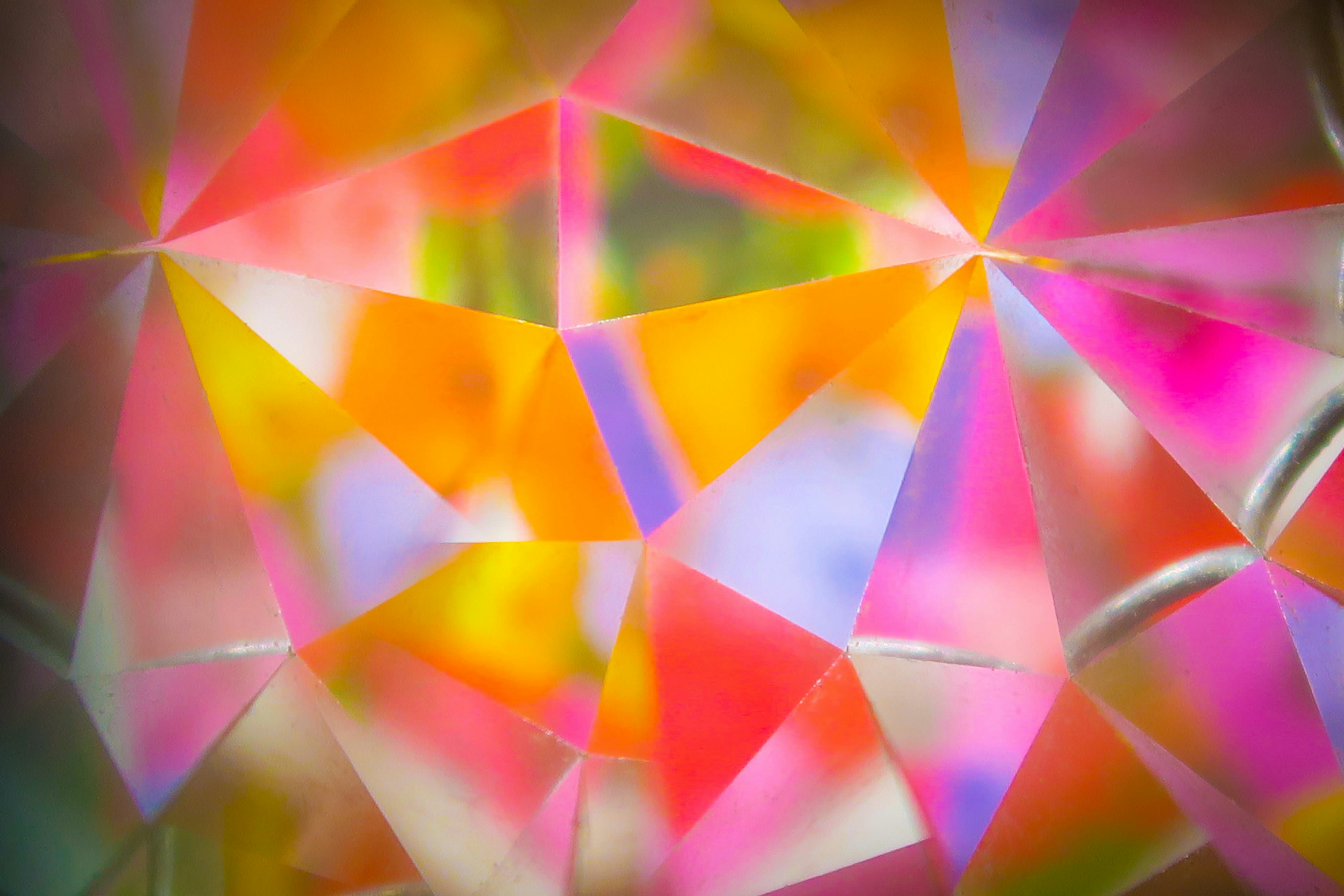 A glass prism bending light into a colorful rainbow spectrum on a dark background.