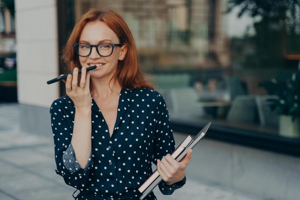 Woman records voice message instead of typing to avoid accidents in streets by avoiding typing.