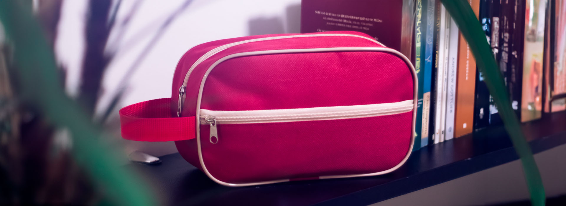 Uma necessaire vermelha em uma prateleira ao lado de vários livros