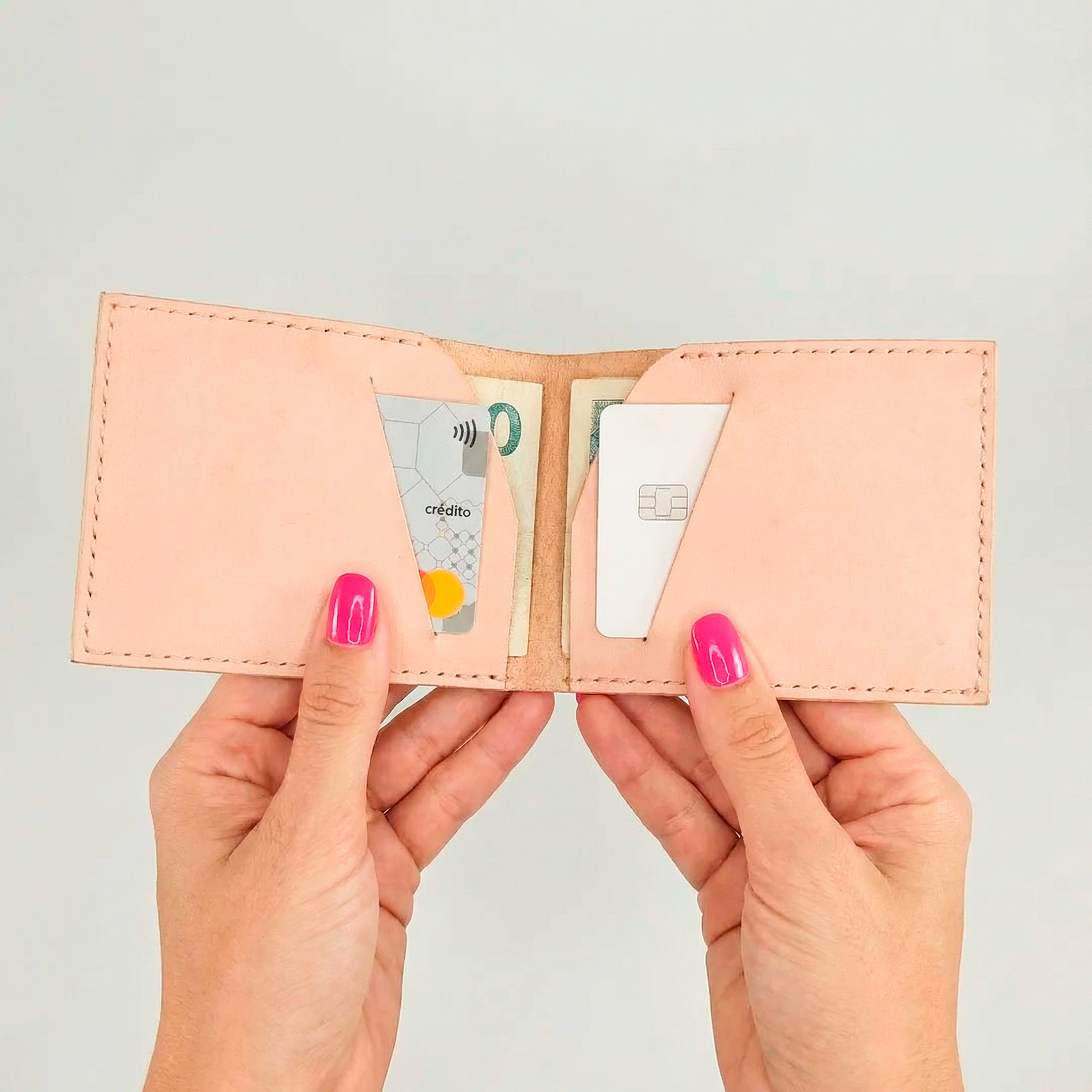 uma carteira rosa aberta nas mãos de uma mulher