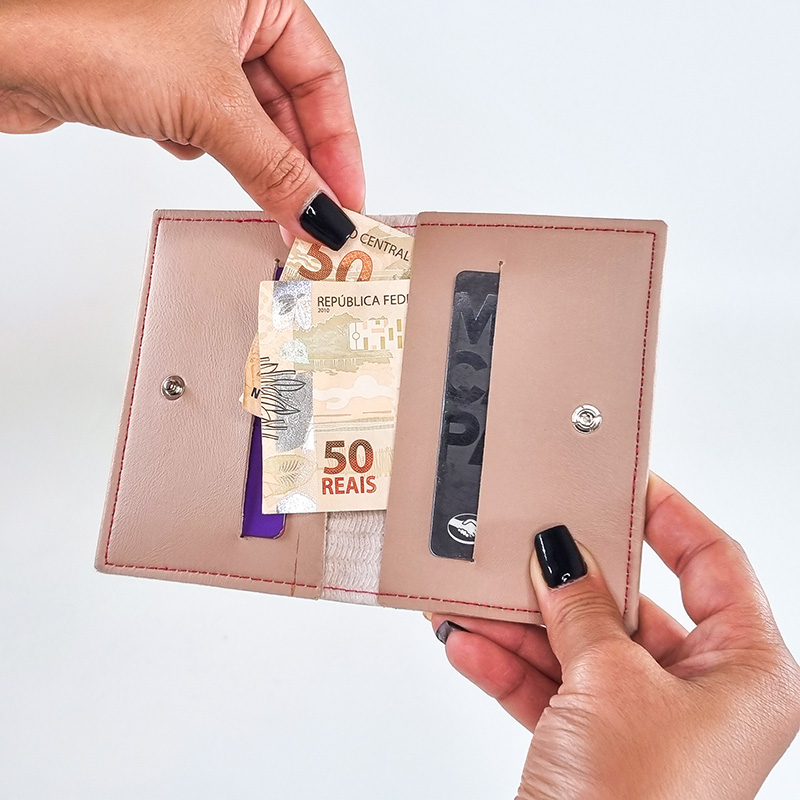 uma mão segurando uma carteira bege