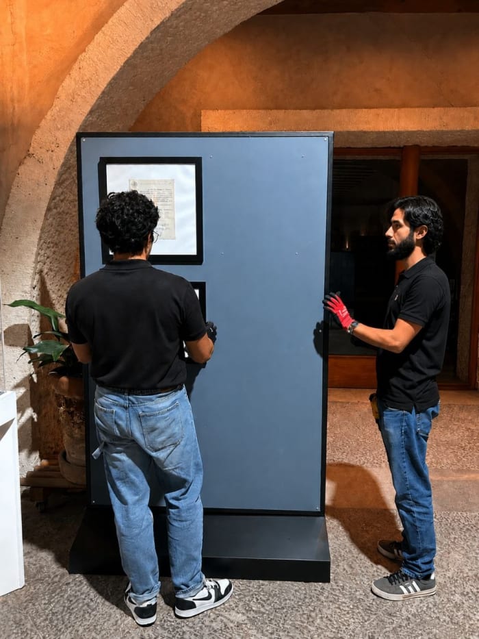 Dos integrantes del equipo levantando e instalando una mampara expositiva en sitio