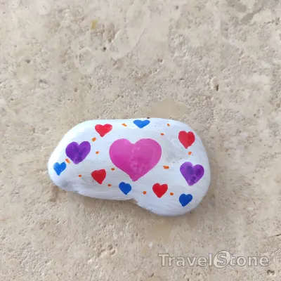 Painted painting stone by artist CJ showing pattern. TravelStone with hearts.