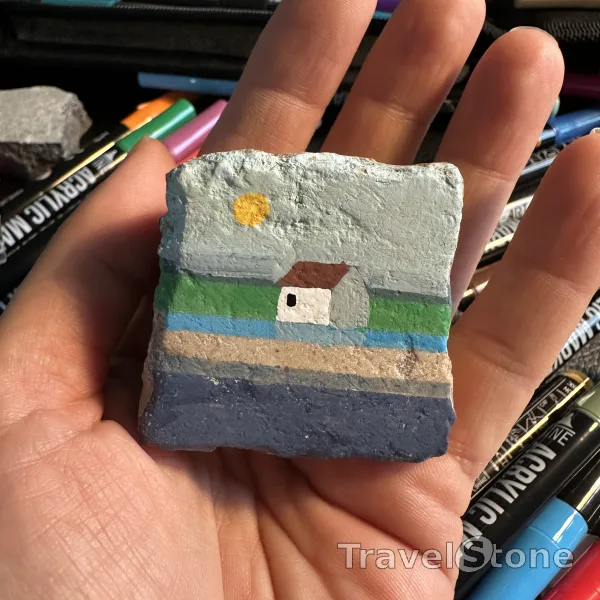 Painted painting stone by artist Birthe_Lucky_Stone showing landscape. Ein stilles Häuschen am Meer, wo die Sonne sanft scheint und die Zeit ein wenig langsamer vergeht. Dieses kleine Gemälde fängt die schlichte Schönheit Dänemarks ein – ruhig, gemütlich und voller Charme. Der Stein erinnert an Momente der Stille, frische Meeresluft und das warme Gefühl, nach Hause zu kommen. Wenn es dir gefällt, nimm es mit – und wenn der richtige Moment gekommen ist, gib es weiter und lass es neue Orte entdecken. A quiet house by the sea, where the sun shines gently and time slows down. This peaceful scene captures the simple beauty of Danish life – calm, cozy, and full of quiet charm. Let this stone remind you of still moments, fresh breezes, and the feeling of coming home. Feel free to take it with you on your journey – and when the time feels right, pass it along and let it continue to travel. Every stop adds a little more to its story