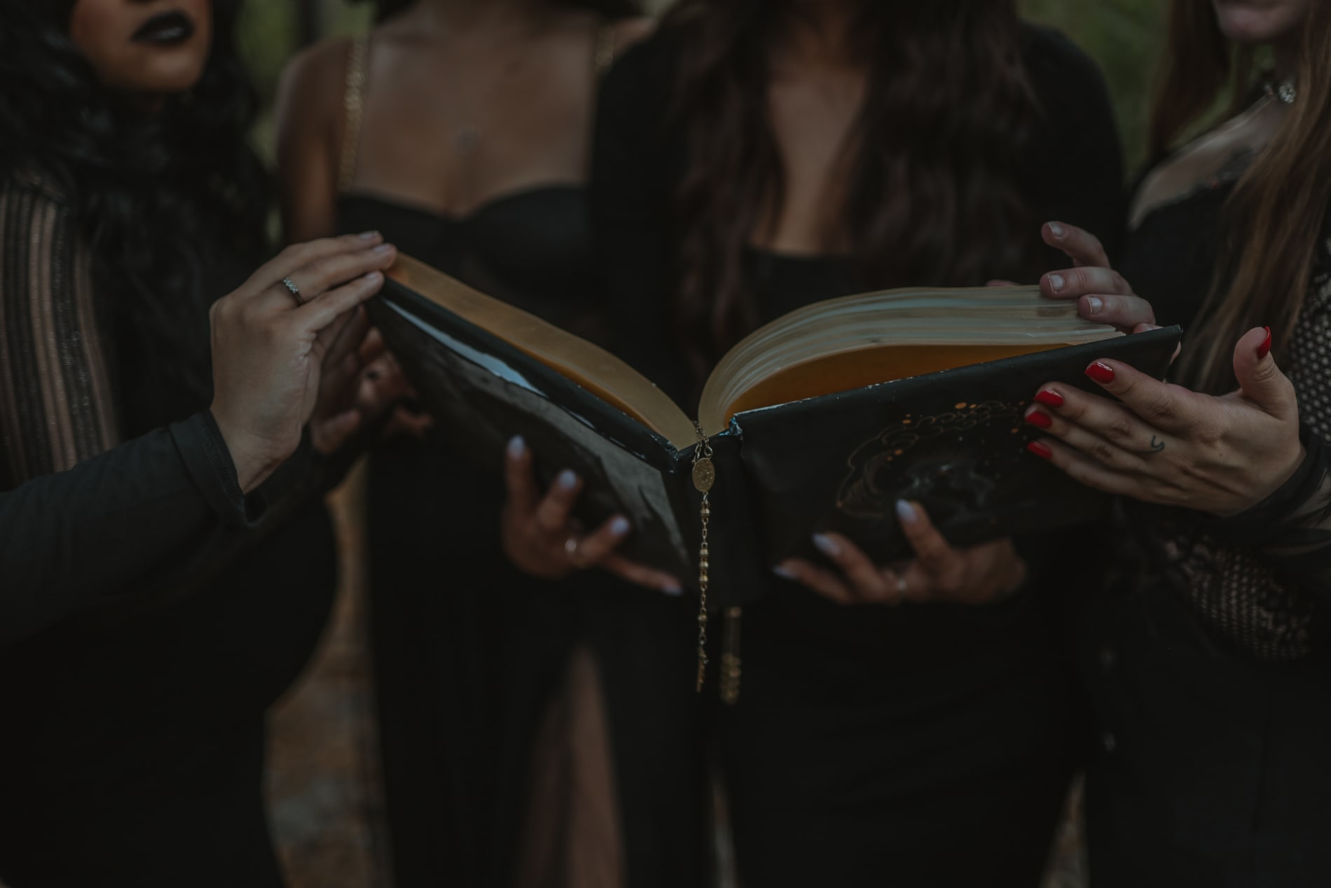 A group of women, implied to be witches, standing next to each other holding a book