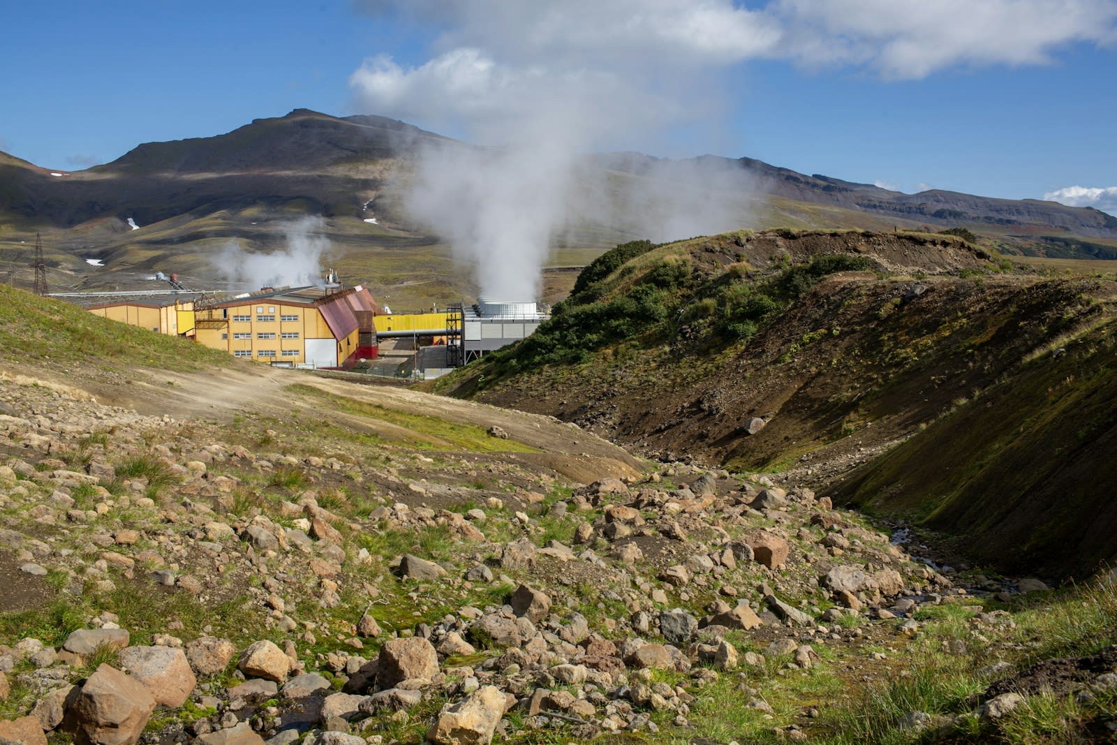 Geothermal power infrastructure with steam plumes rising from cooling towers
