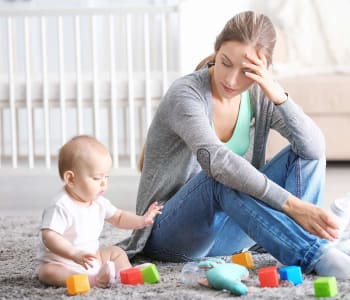 maman en dépression post-partum en train de regarder son enfant jouer